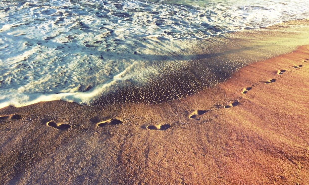 Footsteps across an open beach